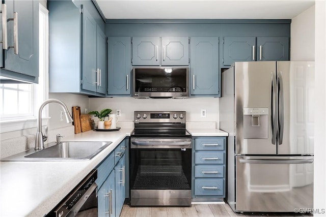 kitchen featuring a sink, light wood-style floors, appliances with stainless steel finishes, and light countertops