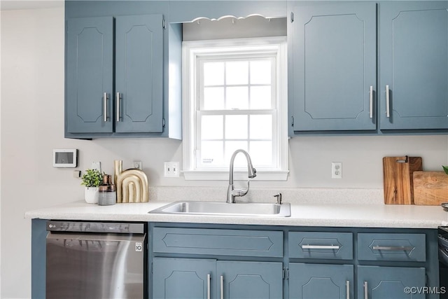 kitchen with stainless steel dishwasher, light countertops, blue cabinetry, and a sink