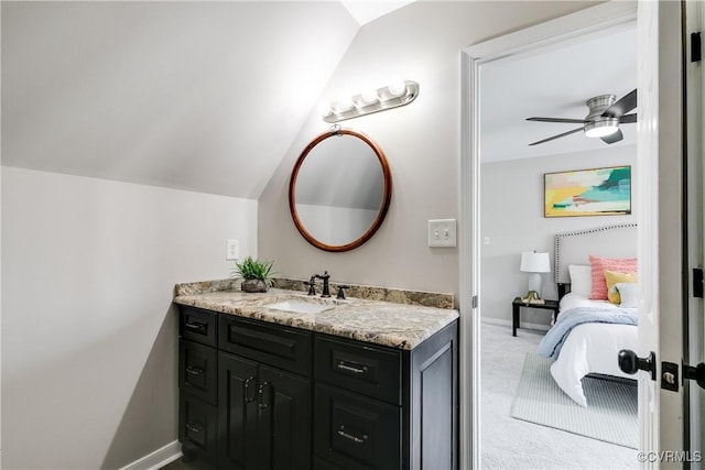 bathroom with vanity, vaulted ceiling, a ceiling fan, and baseboards