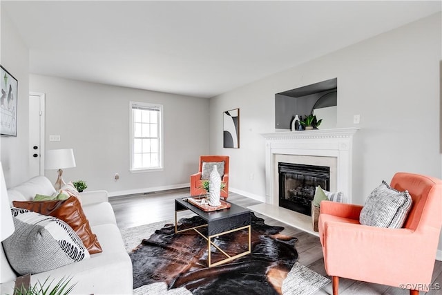 living room featuring a fireplace with flush hearth, wood finished floors, and baseboards