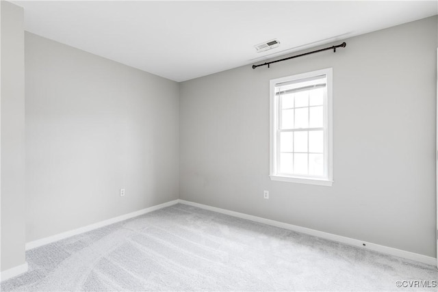 carpeted spare room with visible vents and baseboards