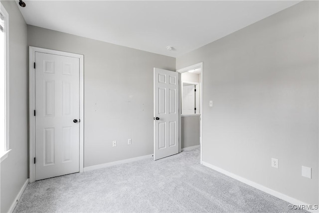 unfurnished bedroom with baseboards and light carpet