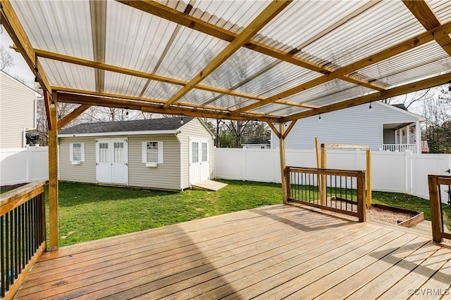 wooden terrace featuring a lawn, a fenced backyard, and an outdoor structure