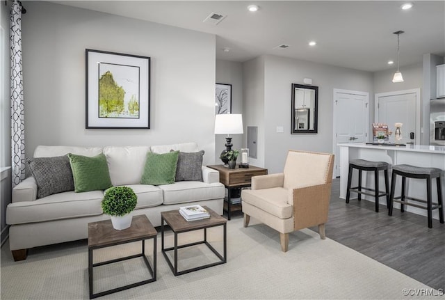 living area with wood finished floors, visible vents, and recessed lighting