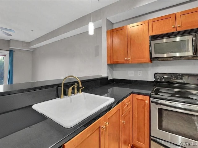 kitchen featuring stainless steel appliances, brown cabinetry, dark countertops, and a sink