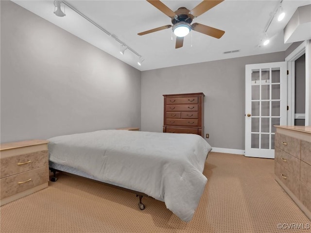 bedroom featuring light carpet, rail lighting, visible vents, and a ceiling fan