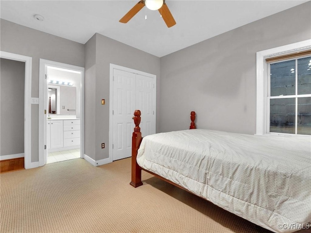 bedroom with connected bathroom, light carpet, a ceiling fan, baseboards, and a closet