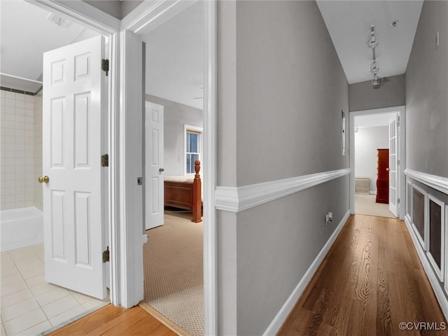 corridor with track lighting, baseboards, and wood finished floors