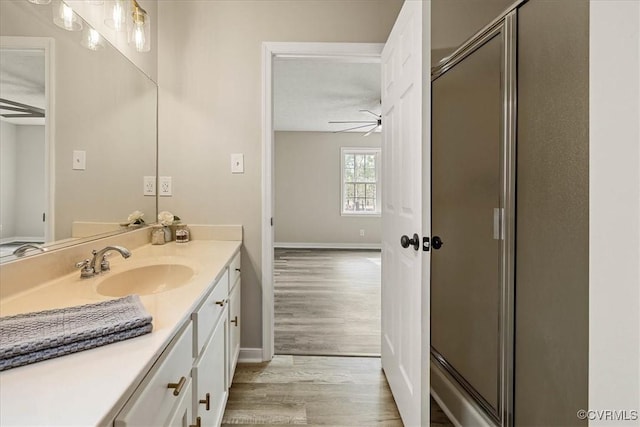 bathroom featuring a shower stall, vanity, ceiling fan, and wood finished floors