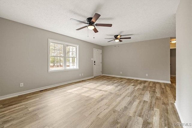 unfurnished room featuring a ceiling fan, baseboards, visible vents, light wood-style flooring, and a textured ceiling