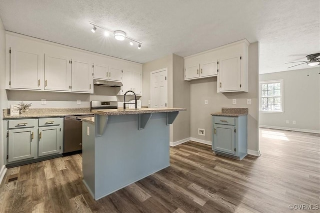 kitchen with under cabinet range hood, stainless steel appliances, a textured ceiling, white cabinetry, and a ceiling fan