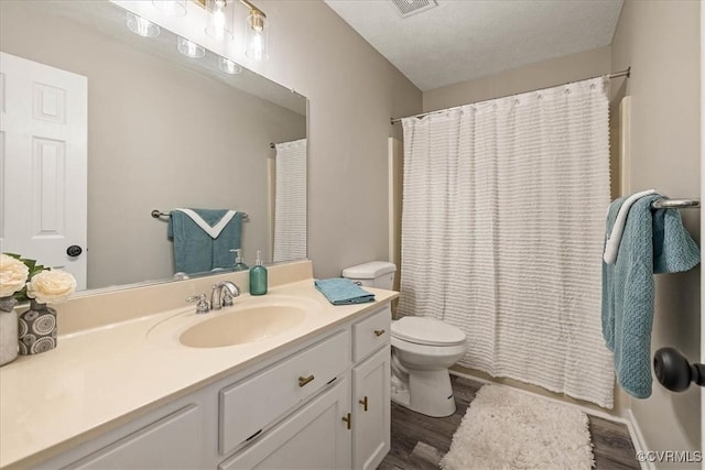 full bath featuring toilet, wood finished floors, vanity, and a textured ceiling