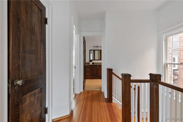 corridor with an upstairs landing and light wood-type flooring