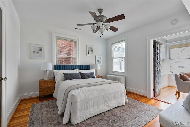 bedroom featuring light wood finished floors, visible vents, radiator, ceiling fan, and baseboards