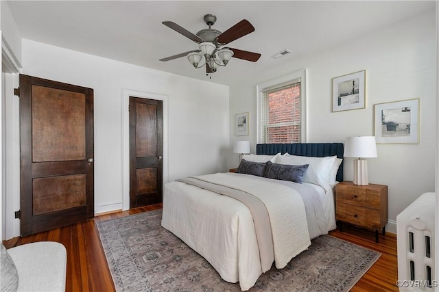 bedroom with baseboards, wood finished floors, visible vents, and ceiling fan