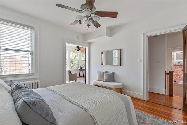 bedroom featuring a ceiling fan, radiator heating unit, baseboards, and light wood-type flooring