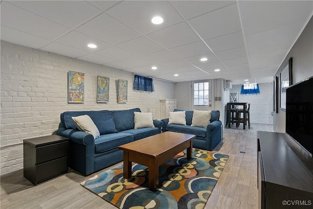 living room featuring brick wall, a paneled ceiling, recessed lighting, and light wood finished floors