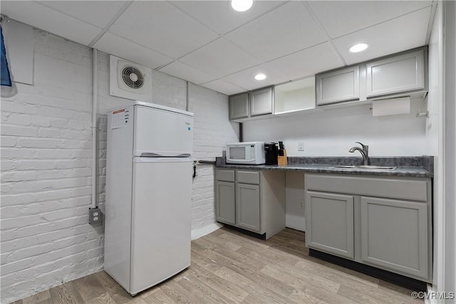 kitchen featuring white appliances, visible vents, a sink, gray cabinetry, and dark countertops