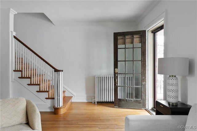 entryway featuring stairway, radiator, wood finished floors, baseboards, and ornamental molding