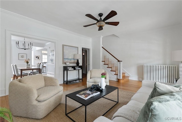 living area with crown molding, radiator, stairs, and wood finished floors