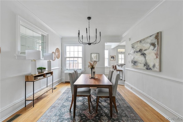 dining area featuring visible vents, wood finished floors, radiator heating unit, and ornamental molding