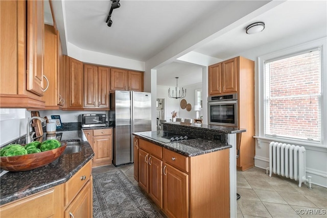 kitchen featuring radiator, a kitchen island, dark stone counters, a wealth of natural light, and appliances with stainless steel finishes