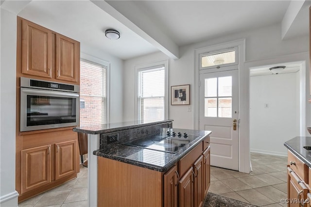 kitchen featuring a center island, dark stone counters, stainless steel oven, black electric stovetop, and light tile patterned floors