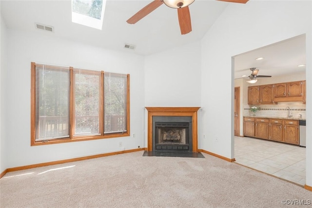 unfurnished living room featuring visible vents, light colored carpet, a fireplace with flush hearth, and ceiling fan