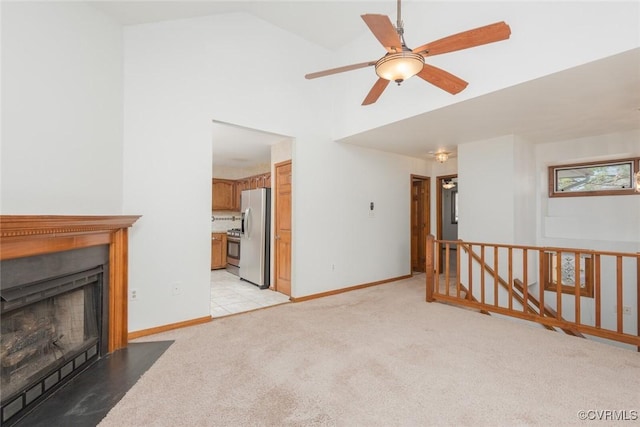 living room with baseboards, a fireplace with flush hearth, light carpet, high vaulted ceiling, and a ceiling fan