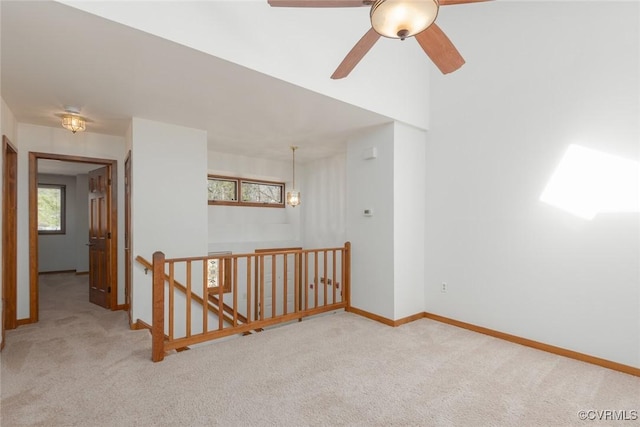 carpeted empty room with ceiling fan and baseboards