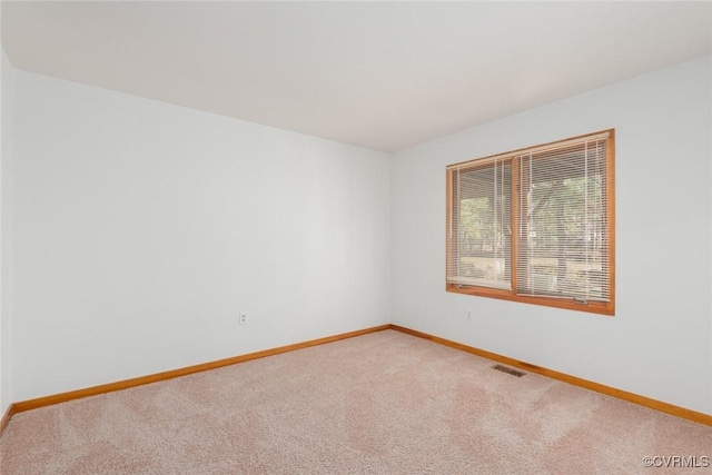 spare room with visible vents, light carpet, and baseboards