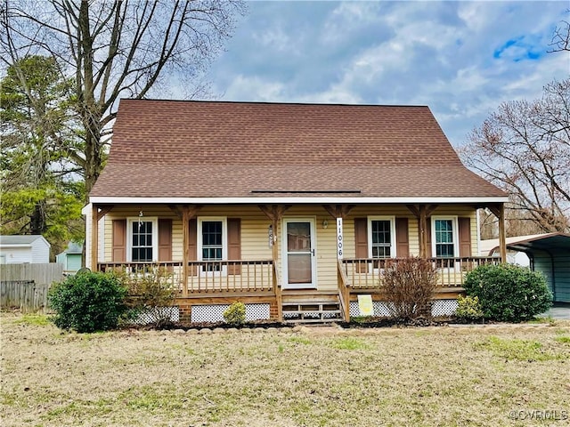 view of front of house with covered porch, a shingled roof, a front yard, and a detached carport