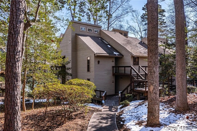 back of house featuring stairway and roof with shingles