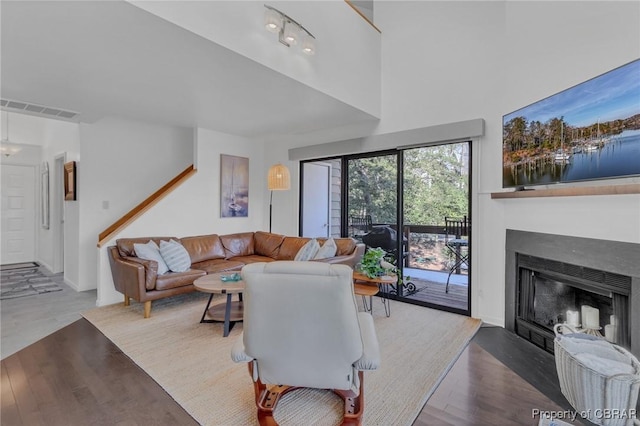 living room featuring a fireplace with flush hearth, wood finished floors, and visible vents