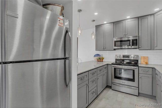 kitchen featuring light stone counters, tasteful backsplash, gray cabinets, and appliances with stainless steel finishes