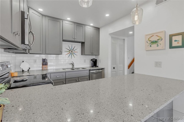 kitchen with gray cabinets, light stone countertops, stainless steel appliances, and a sink