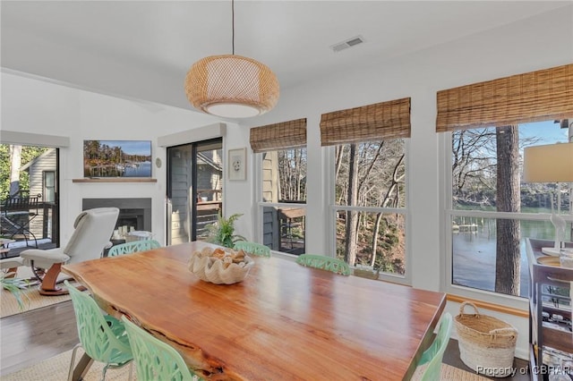 dining area featuring visible vents, a fireplace, and wood finished floors