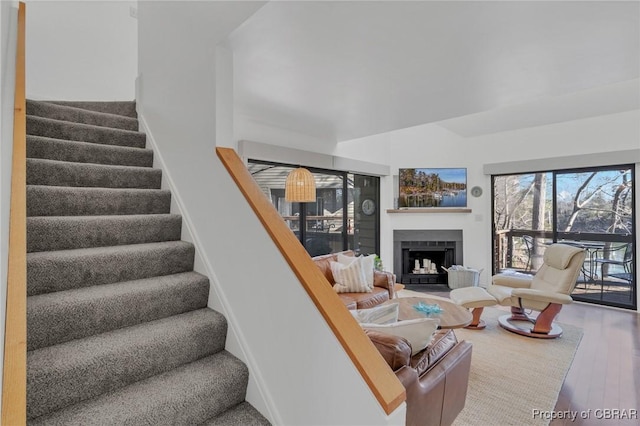 living area featuring stairway, a fireplace with flush hearth, and wood finished floors