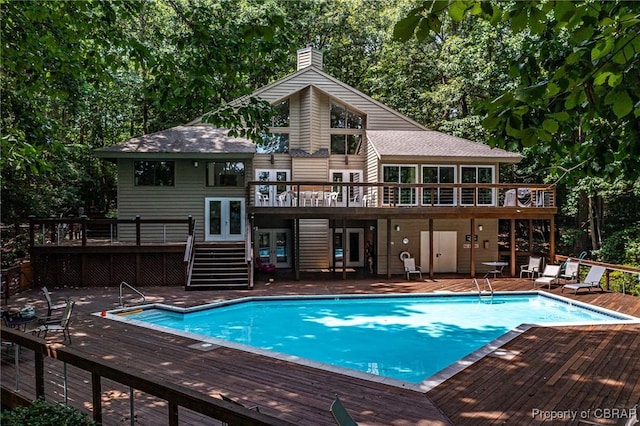 pool featuring a deck, a patio area, stairs, and french doors