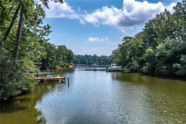 view of water feature with a forest view and a dock