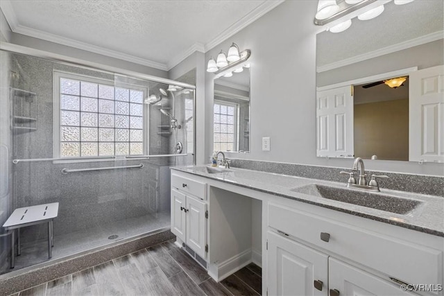 full bath with a shower stall, ornamental molding, a sink, and wood finish floors