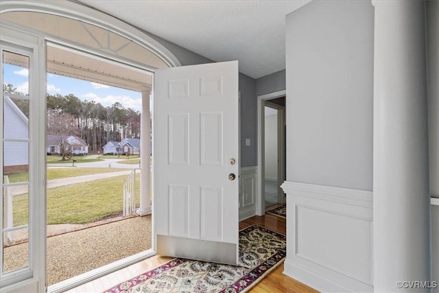 doorway featuring a decorative wall, wood finished floors, and wainscoting