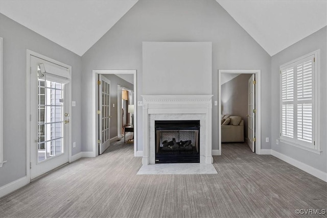 unfurnished living room with high vaulted ceiling, carpet, a high end fireplace, and baseboards