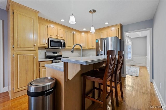 kitchen featuring hanging light fixtures, appliances with stainless steel finishes, light brown cabinets, and light wood-style floors