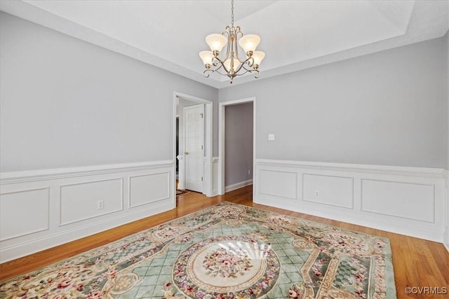 unfurnished room with light wood finished floors, a chandelier, and a decorative wall