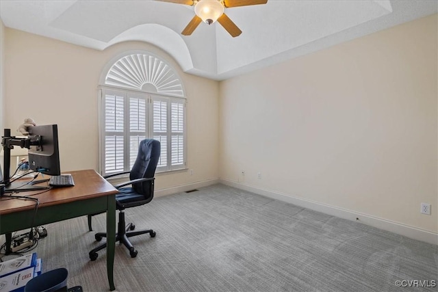 office area with carpet floors, a tray ceiling, a ceiling fan, and baseboards