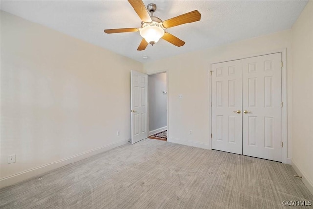 unfurnished bedroom with a closet, carpet, a ceiling fan, and baseboards