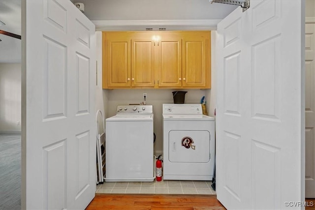 washroom with light wood-type flooring, cabinet space, and washing machine and clothes dryer