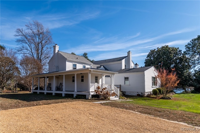 view of front of property with covered porch, a chimney, and a front lawn