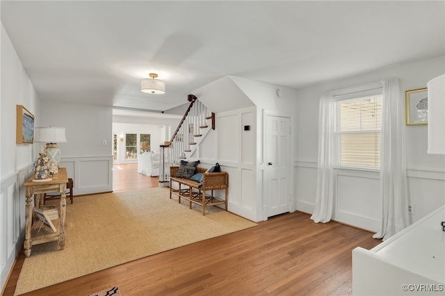 foyer with wood finished floors, a wainscoted wall, a decorative wall, and stairs